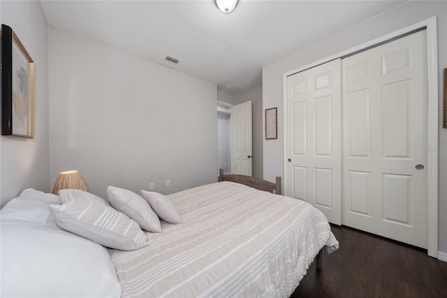 bedroom with dark hardwood / wood-style flooring and a closet