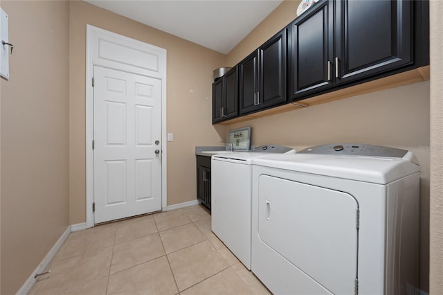 laundry room with light tile patterned floors, washing machine and dryer, and cabinets