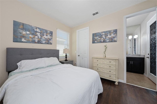 bedroom featuring dark wood-type flooring and connected bathroom