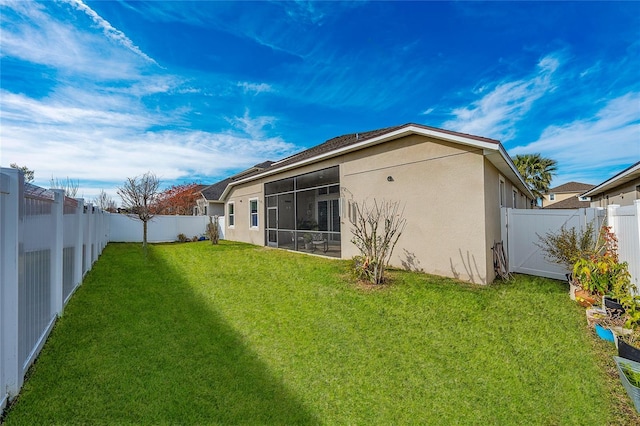 back of property with a sunroom and a lawn