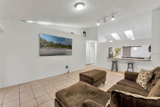 tiled living room with a textured ceiling, rail lighting, and vaulted ceiling with skylight