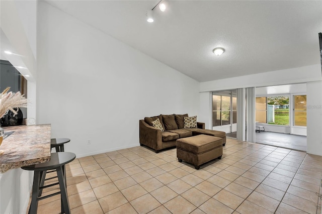 tiled living room featuring rail lighting, lofted ceiling, and a textured ceiling