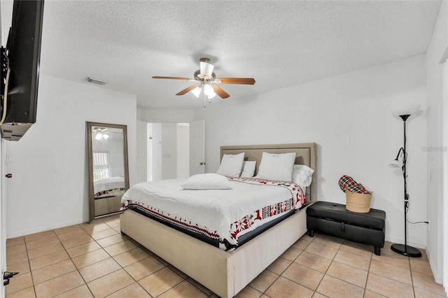 tiled bedroom featuring ceiling fan and a textured ceiling