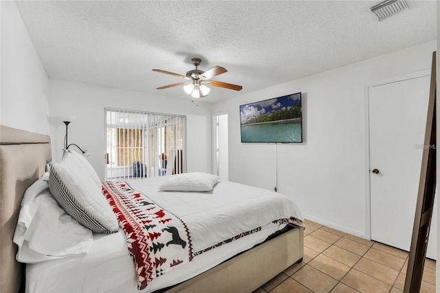 tiled bedroom featuring ceiling fan and a textured ceiling