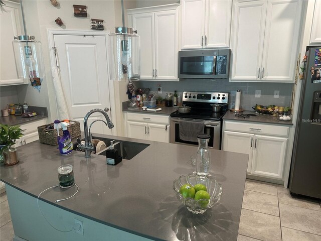 kitchen featuring sink, light tile patterned floors, white cabinetry, stainless steel appliances, and tasteful backsplash