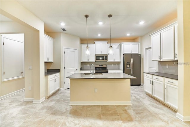 kitchen featuring pendant lighting, sink, white cabinets, stainless steel appliances, and a center island with sink