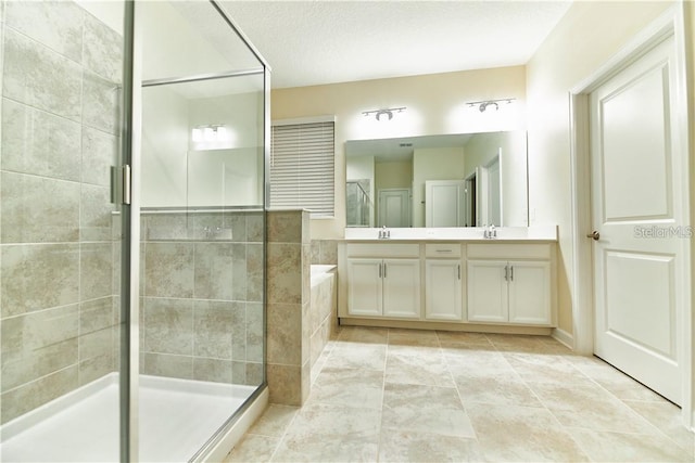 bathroom with vanity, tile patterned floors, a shower with door, and a textured ceiling