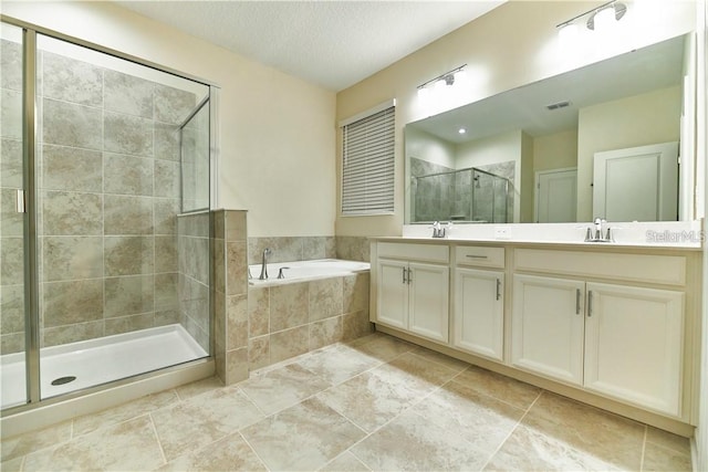 bathroom featuring vanity, tile patterned flooring, plus walk in shower, and a textured ceiling