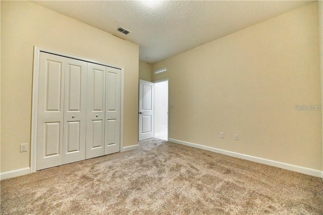 unfurnished bedroom with a closet, a textured ceiling, and carpet