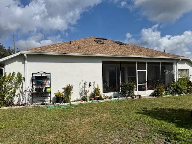 back of property with a lawn and a sunroom