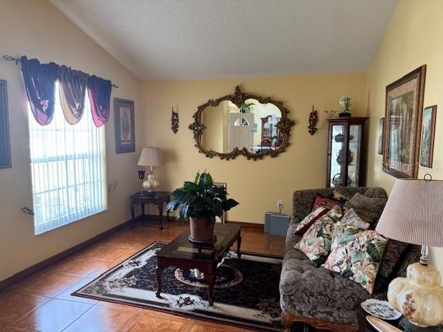 living room with lofted ceiling, tile patterned flooring, and a textured ceiling