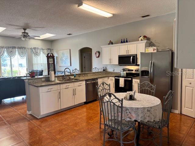 kitchen featuring white cabinetry, sink, kitchen peninsula, stainless steel appliances, and a textured ceiling