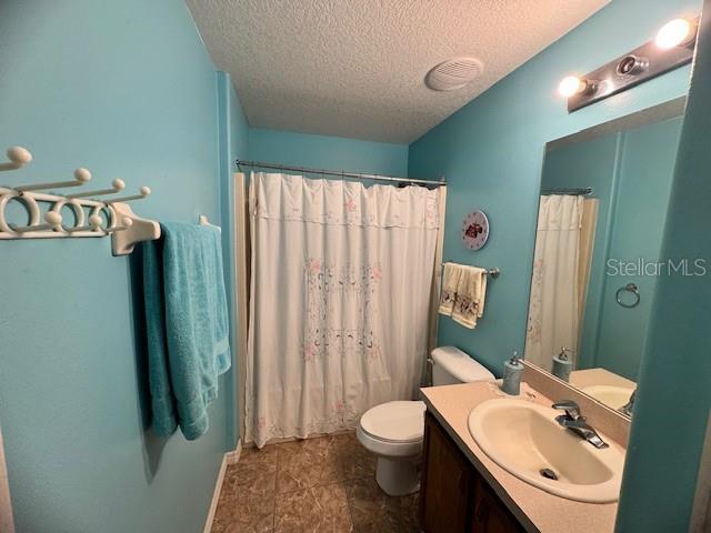 bathroom with vanity, walk in shower, a textured ceiling, and toilet