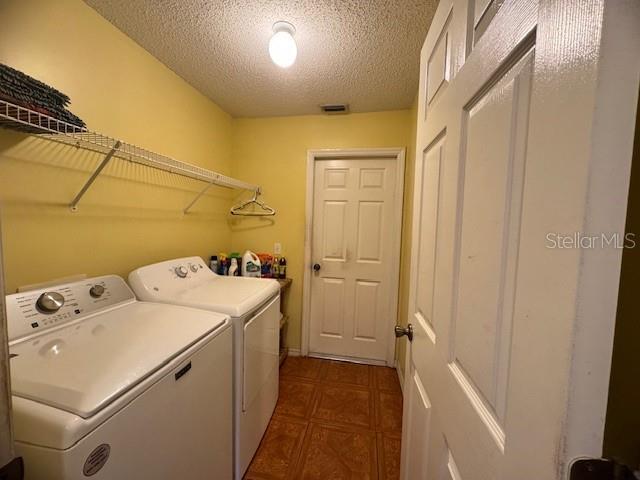 laundry room with a textured ceiling and washing machine and clothes dryer