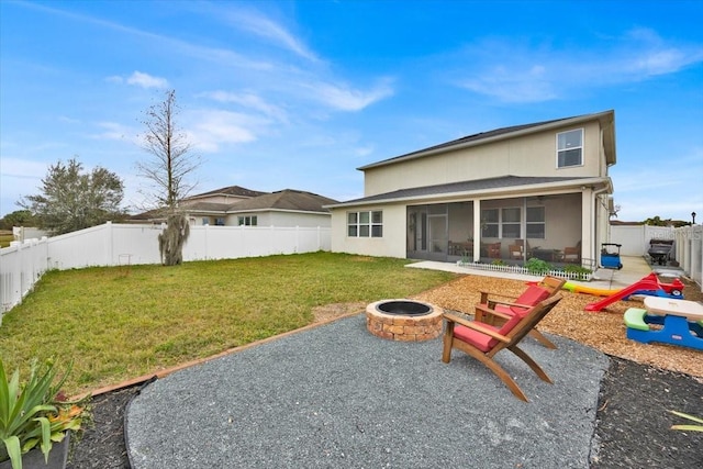 rear view of property featuring a patio, a sunroom, a lawn, and an outdoor fire pit