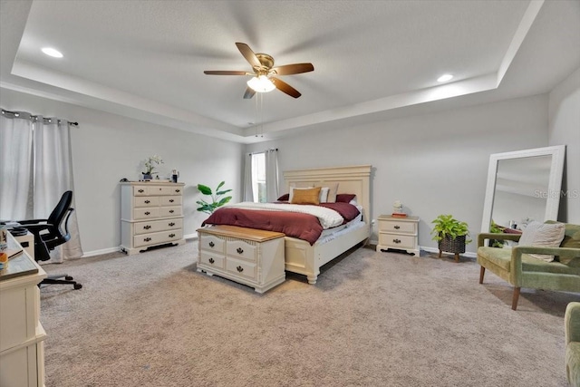 carpeted bedroom featuring ceiling fan and a tray ceiling