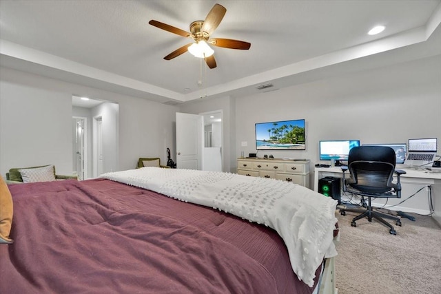 carpeted bedroom with a raised ceiling and ceiling fan