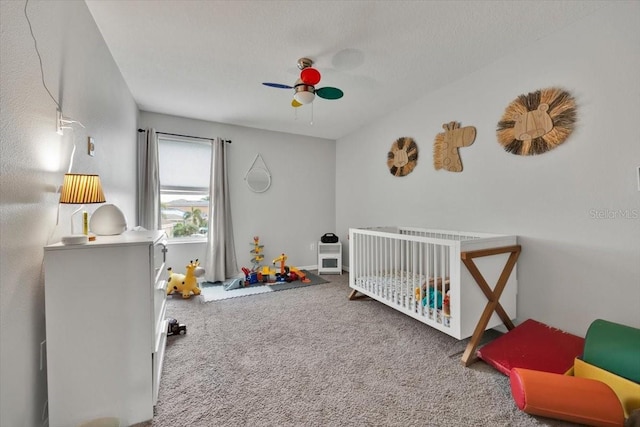 bedroom with ceiling fan, a textured ceiling, carpet, and a crib