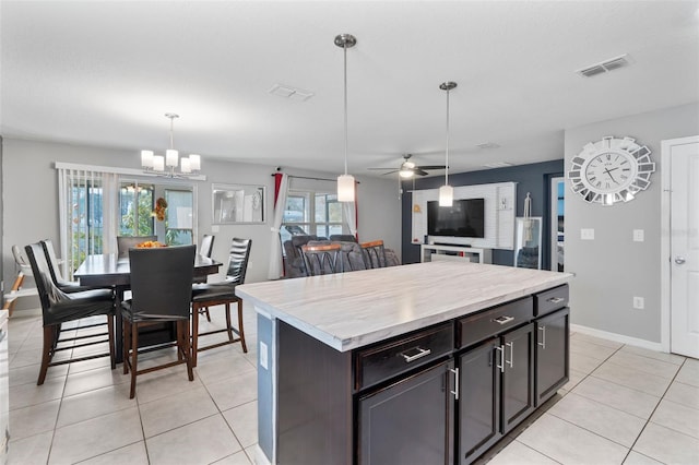 kitchen featuring a kitchen island, dark brown cabinets, pendant lighting, and light tile patterned floors