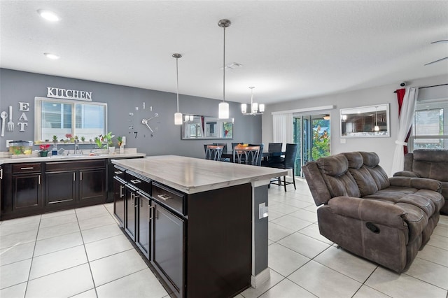 kitchen featuring a kitchen island, sink, light tile patterned floors, and decorative light fixtures