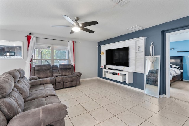 living room featuring ceiling fan, light tile patterned flooring, and a textured ceiling