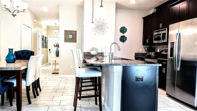 kitchen featuring pendant lighting, sink, a breakfast bar, stainless steel appliances, and an island with sink