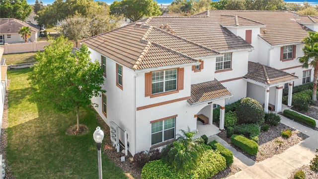 mediterranean / spanish house with stucco siding, a tile roof, and a front yard