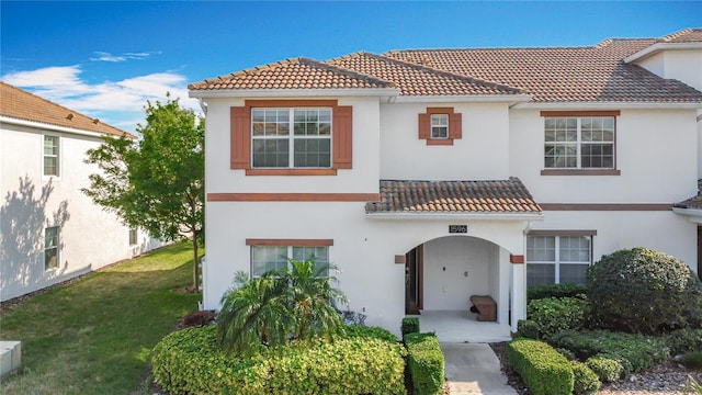 mediterranean / spanish-style home featuring stucco siding, a tile roof, and a front yard