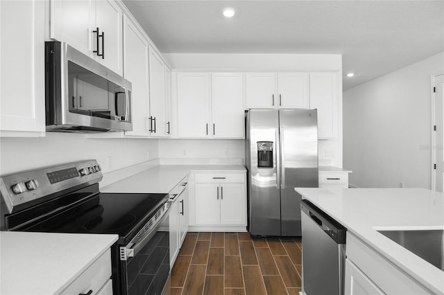 kitchen featuring white cabinets, stainless steel appliances, light countertops, and wood finish floors