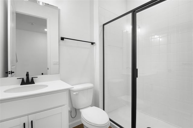 bathroom with toilet, a stall shower, and vanity