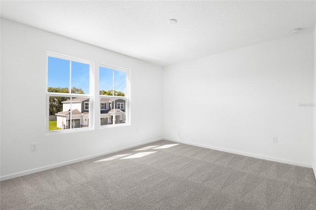 carpeted empty room with baseboards