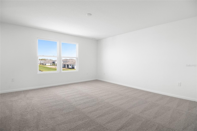 unfurnished room with carpet and baseboards