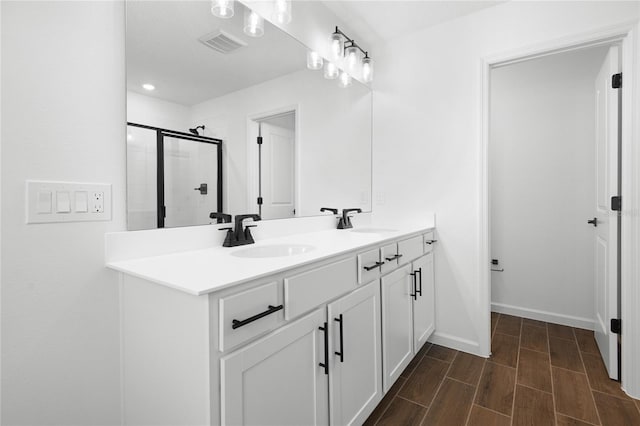 full bathroom with double vanity, a stall shower, a sink, and visible vents