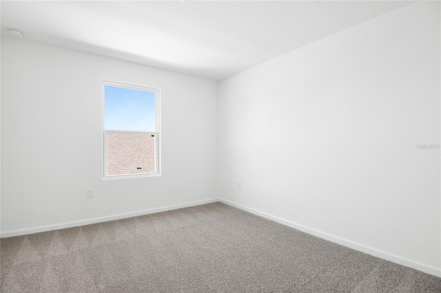 carpeted spare room featuring baseboards