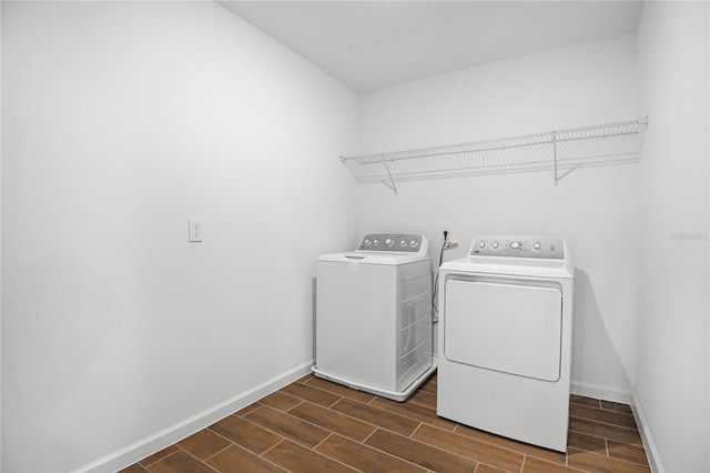 laundry area featuring wood tiled floor, laundry area, baseboards, and separate washer and dryer