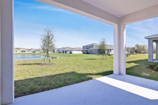 view of yard featuring a residential view, a patio area, and a water view