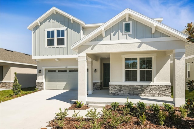 craftsman house with a garage, stone siding, board and batten siding, and concrete driveway