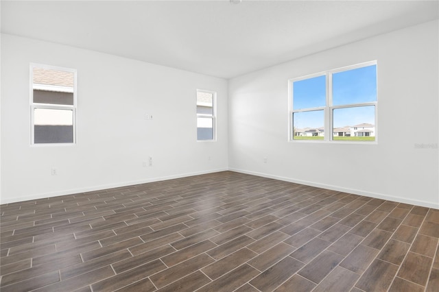 spare room with baseboards and dark wood-style flooring