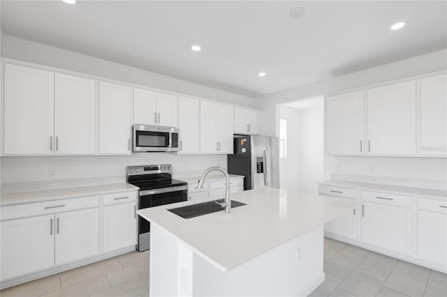 kitchen with appliances with stainless steel finishes, a sink, a kitchen island with sink, and white cabinets