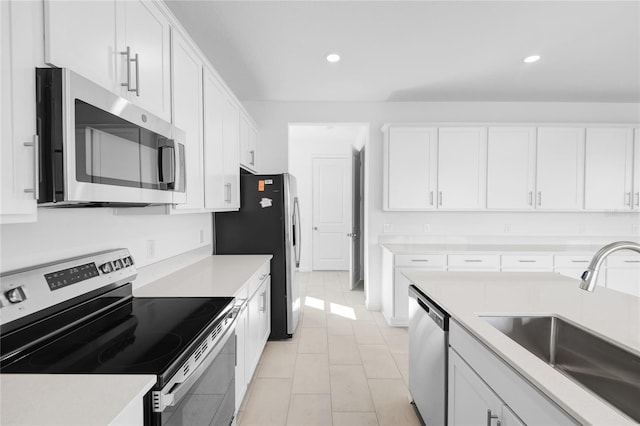 kitchen featuring white cabinetry, stainless steel appliances, a sink, and light countertops