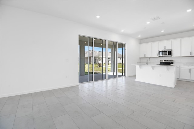 kitchen featuring stainless steel appliances, visible vents, a kitchen breakfast bar, open floor plan, and light countertops