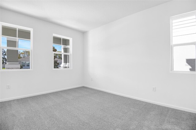 spare room featuring carpet floors, a wealth of natural light, and baseboards