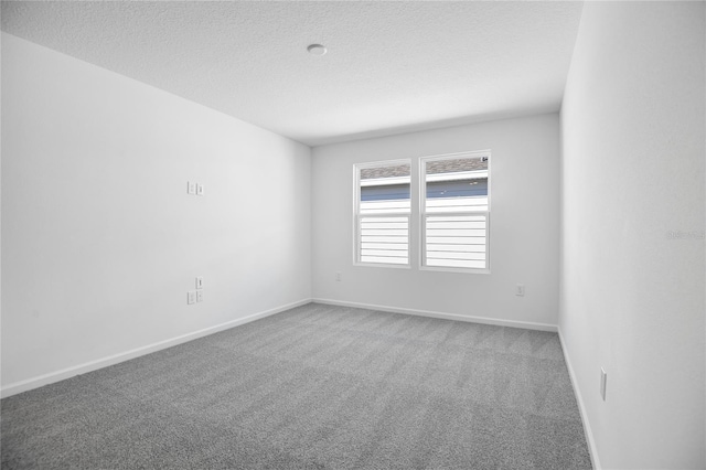 carpeted spare room featuring a textured ceiling and baseboards