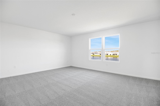 unfurnished room featuring carpet and baseboards