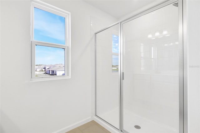 full bathroom featuring baseboards, tile patterned flooring, a shower stall, and a healthy amount of sunlight