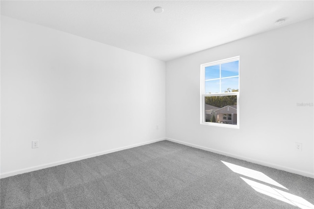 carpeted empty room featuring baseboards