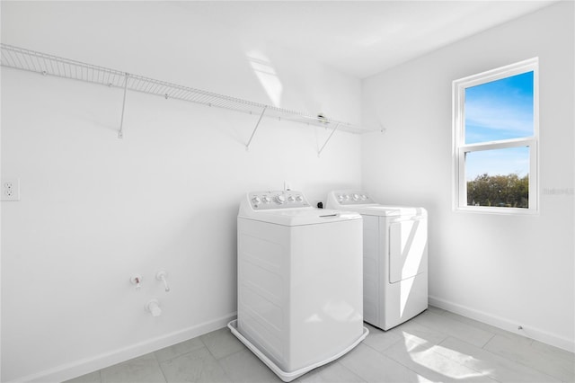 washroom featuring laundry area, baseboards, and washing machine and clothes dryer