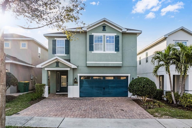 traditional home featuring a garage, decorative driveway, and stucco siding