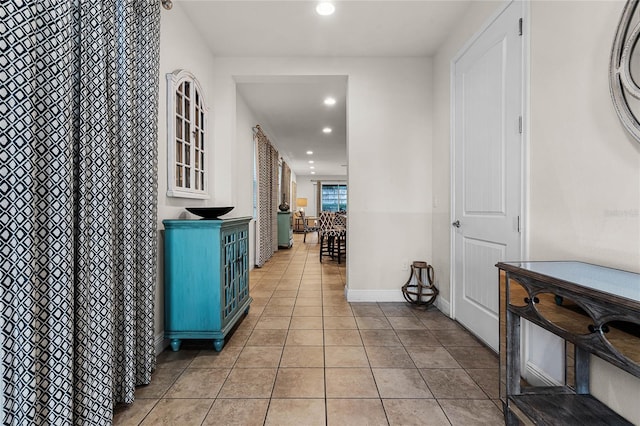 hallway featuring recessed lighting, baseboards, and light tile patterned flooring