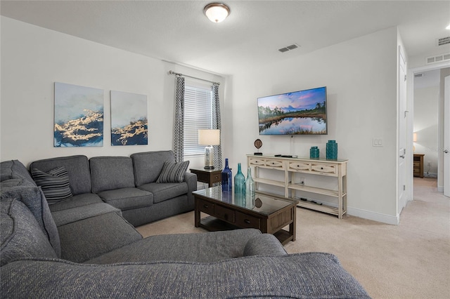 living area featuring baseboards, visible vents, and light colored carpet